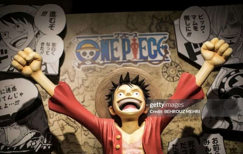 One Piece Manga's main character, Luffy, raising hands in the air cheering with the One Piece logo and map in the background.